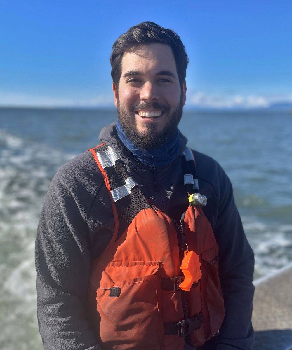 Jeremy Corbin in an orange floater jacket beside the water