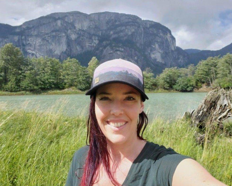 Mika Davis in a ball cap in front of a wetland and mountain